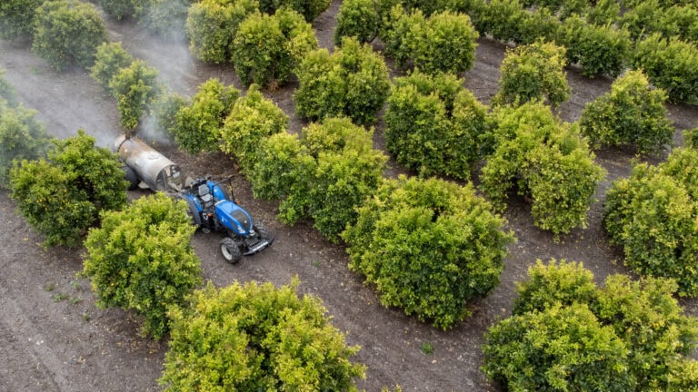 An automated tractor pulls a sprayer through a field. Photo courtesy of Bluewhite