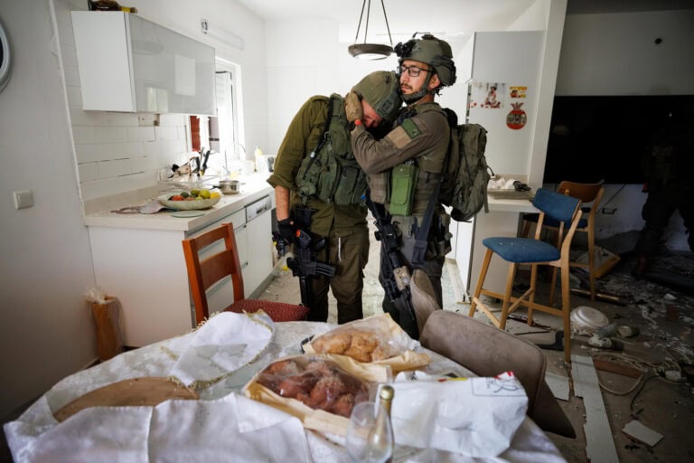 Soldiers weep in the wreckage of a home at Kibbutz Kfar Aza, where leftover wine and challah from a holiday meal are still on the table, four days after the October 7 massacre. Photo by Ziv Koren/Polaris Images