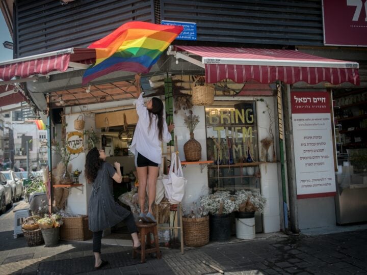 A woman hangs a Pride flag in the Florentin neighborhood in Tel Aviv, June 3, 2024. Photo by Miriam Alster/FLASH90