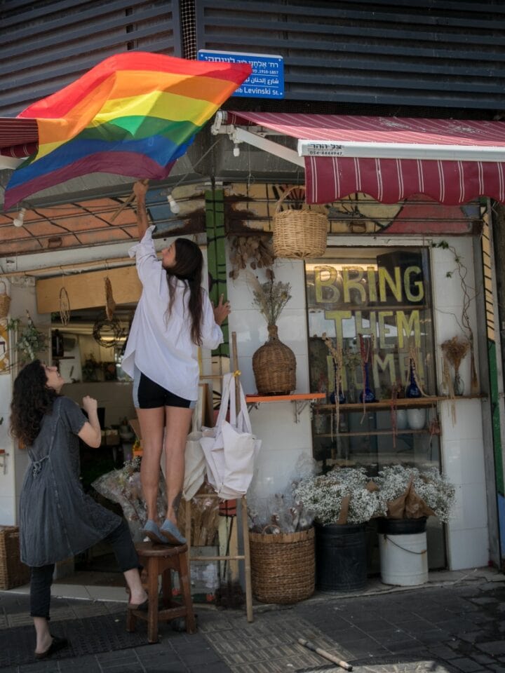 A woman hangs a Pride flag in the Florentin neighborhood in Tel Aviv, June 3, 2024. Photo by Miriam Alster/FLASH90